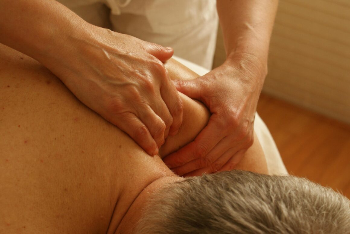 A man is having a massage and they are concentrating on their shoulder and neck muscles