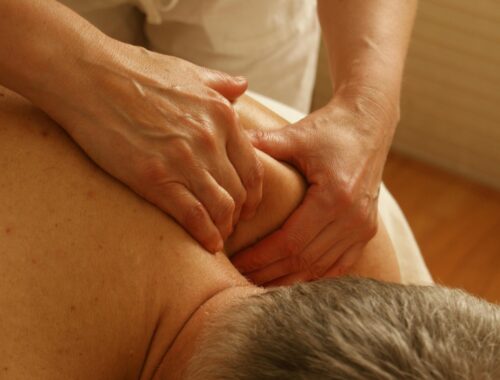 A man is having a massage and they are concentrating on their shoulder and neck muscles