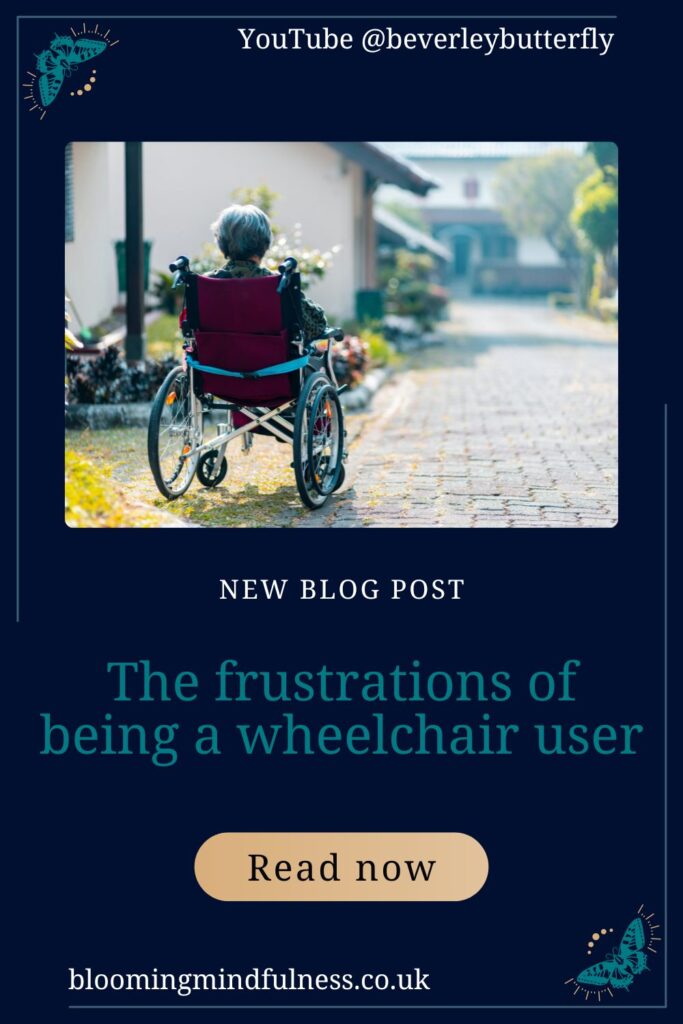 A person seen from behind, is sitting in a wheelchair, alone on a sunny street.