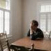 A man is sat at a table, his head is leant on his hand as he looks out of the window