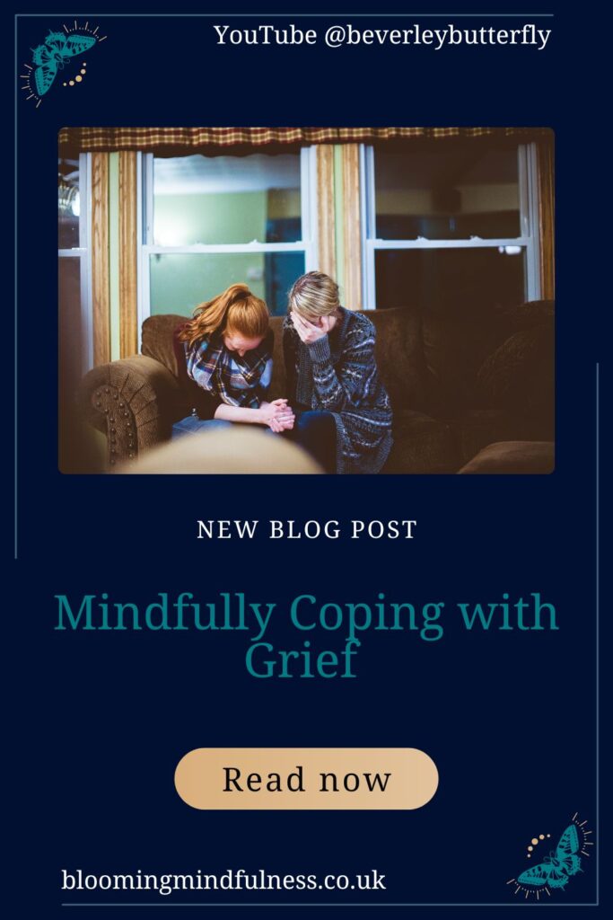 A blonde woman and a redheaded woman are sat huddled on a brown sofa, there is a large window behind them. They are crying and holding one another