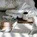 a messy bed with an open book and breakfast spread out on it